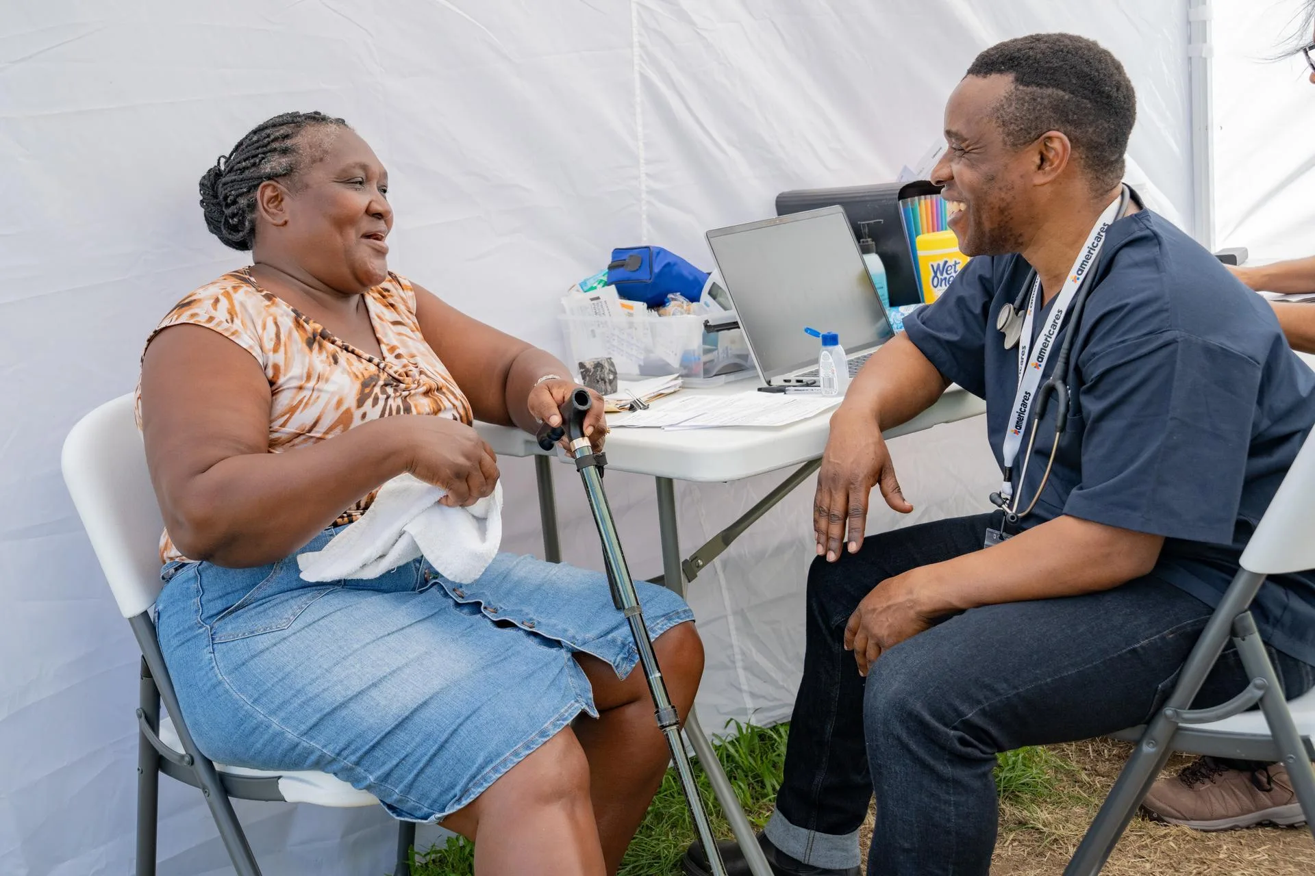 medical professional sitting with woman can in an emergency response tent